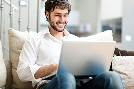 man sitting on the couch looking at his laptop 