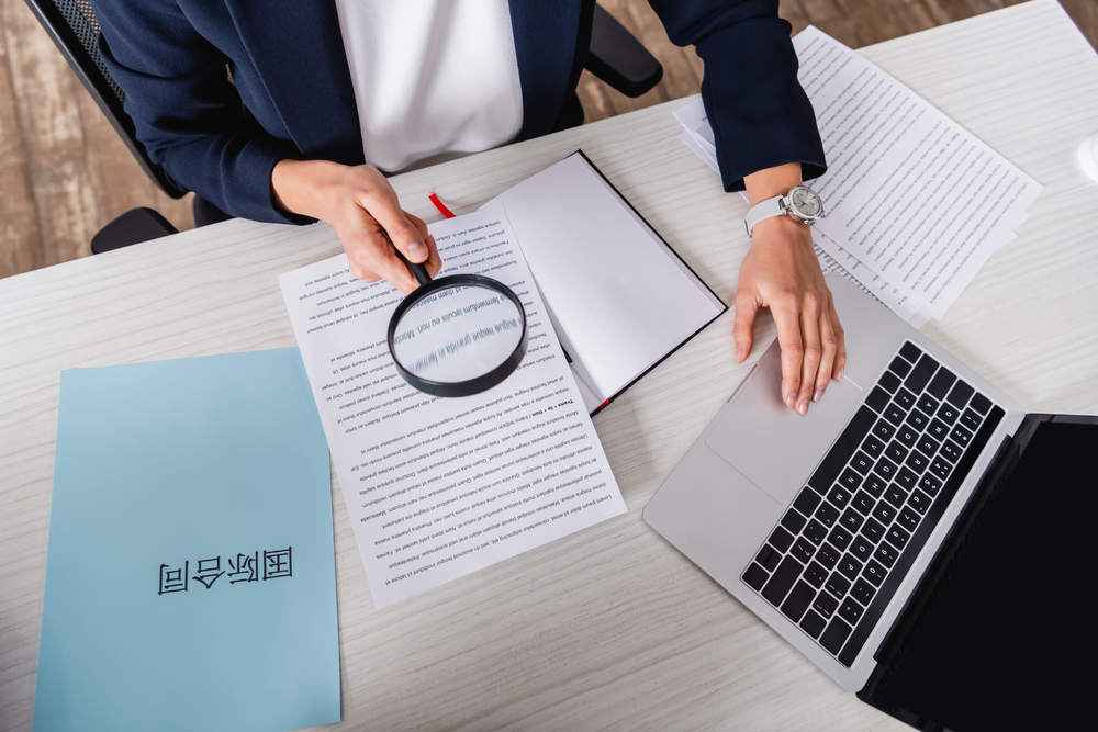 Partial view of a translator with magnifying glass certifying translated documents