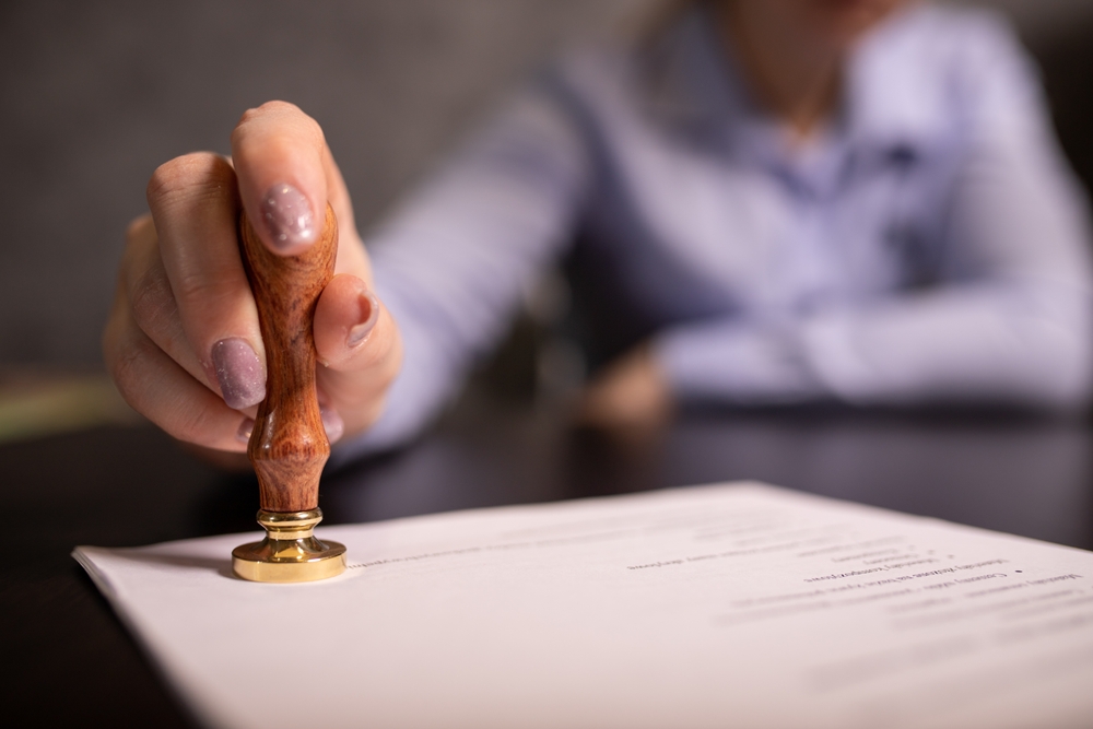 A white document being certified by a golden seal